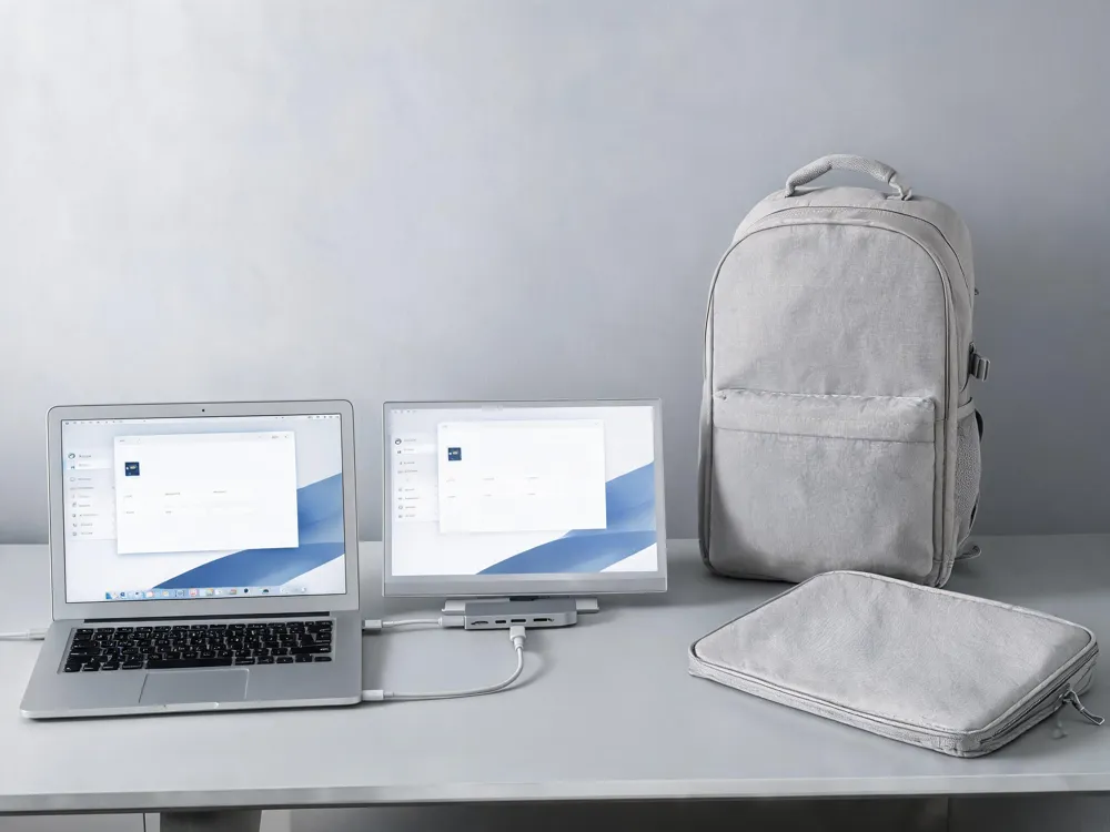 A portable monitor connected to a laptop via a USB‑C hub, with a lightweight backpack and protective sleeve nearby, showing accessories for students on the go.