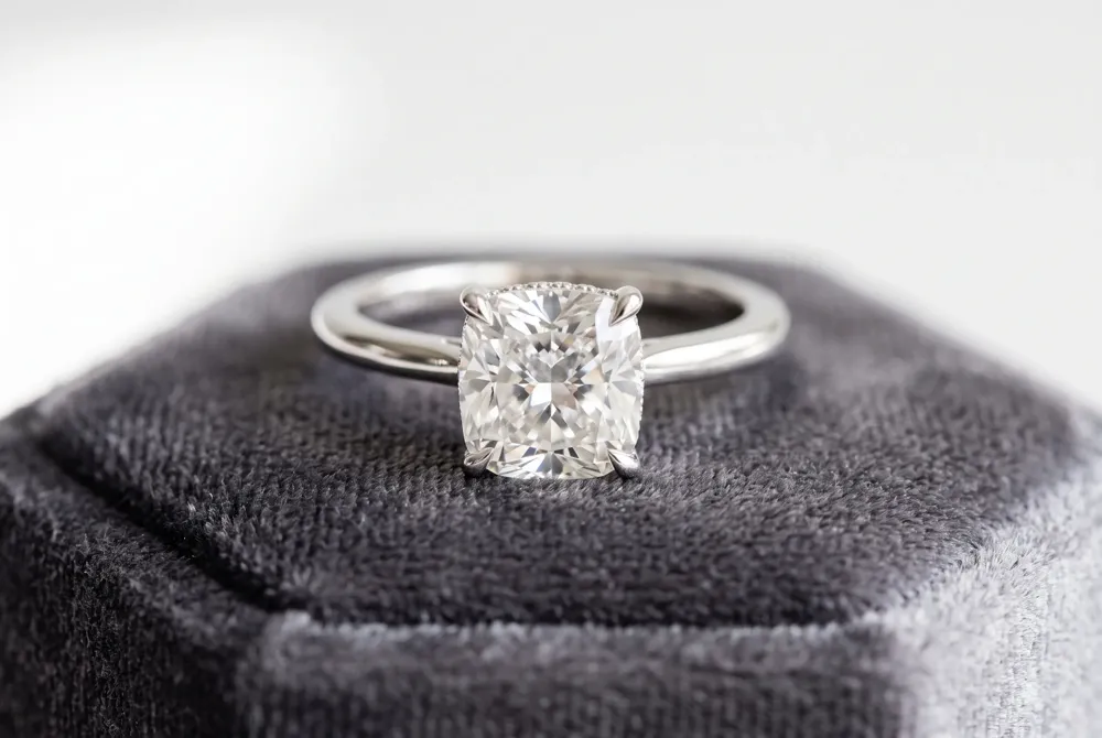 A regal three-stone setting beautifully frames your center cushion cut, symbolizing the past, present, and future with balanced proportions.