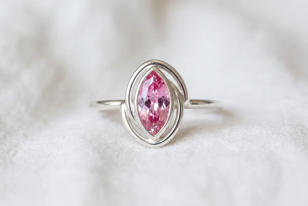 A marquise-cut pink moissanite framed by delicate crescent arcs evokes celestial beauty, intuition, and the promise of new beginnings.