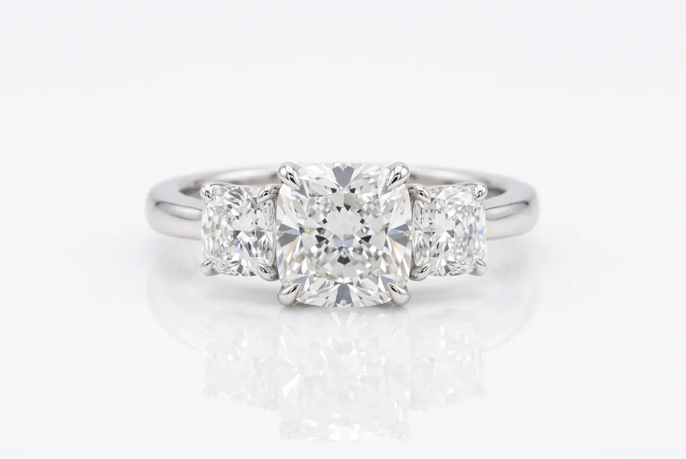 The three-stone setting tells a story of togetherness, with a cushion cut moissanite flanked by accent stones that represent the past, present, and future of your relationship.