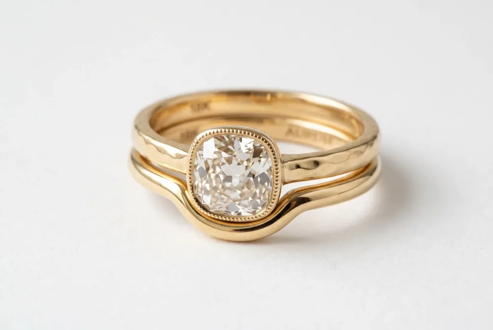 A hand-cut antique diamond set in warm yellow gold paired with a contour wedding band creates a seamless stack that honors vintage charm and modern wearability.