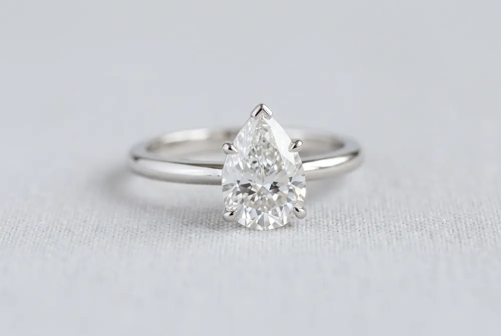 The classic solitaire setting allows the pear-shaped diamond's graceful teardrop silhouette to command attention without distraction, offering exceptional value and a slimming effect on the finger.