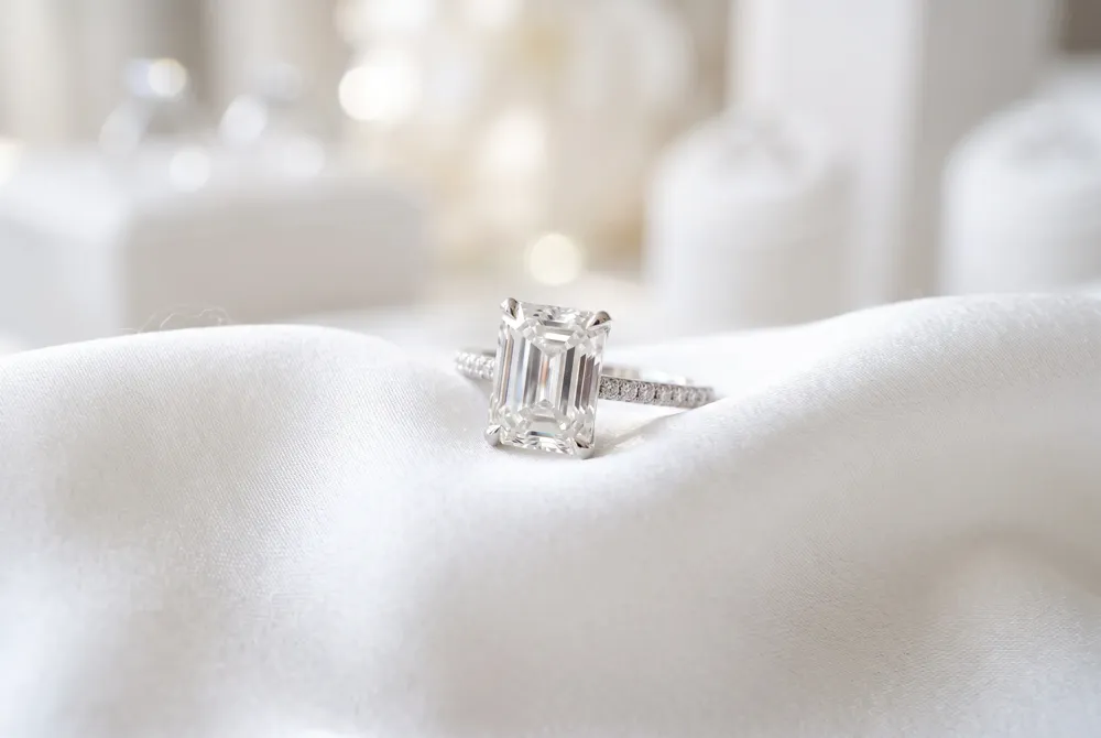 A sparkling pavé halo offers a brilliant frame that complements the structured, step-cut facets of an emerald-cut stone with timeless, radiant elegance.