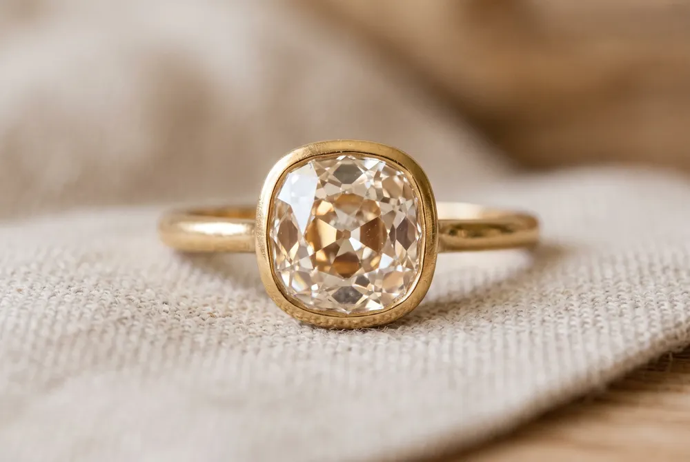 Taylor Swift's ring showcases an antique old mine cut diamond in a bezel setting, a testament to thoughtful artistry and heirloom beauty.