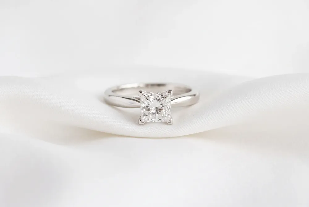 Celebrate your journey with a harmonious three-stone design that pairs a brilliant princess cut centerpiece with balanced side stones for timeless elegance.